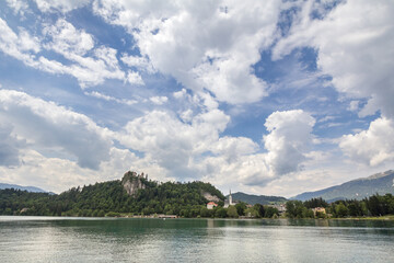 Fototapeta na wymiar Panorama of the Bled lake, Blejsko Jezero, with its castle, Blejski Hrad and the Saint Martin church, or Cerkev Svetog Martina during a sunny afternoon. Bled Castle is a major monument of Slovenia...