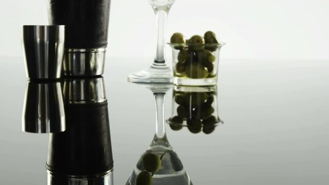 Grey paper burning over bartender equipment and olives in cocktail glass on grey background