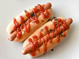 Hot dog with caramelised onion, mustard and tomato ketchup on a plate.