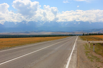 the highway goes beyond the horizon and snowy mountains in the background