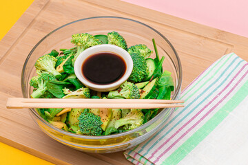 Fresh Green Salad of Avocado, Broccoli, Spinach and Cucumber for Detox with Soy Sauce on Wooden Cutting Board. Vegan Salad. Vegetarian Culture. Raw Food. Healthy Eating and Vegetable Diet