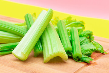 Fresh Celery Stem and Chopped Celery Sticks on Wooden Cutting Board. Vegan and Vegetarian Culture. Raw Food. Healthy Diet with Negative Calorie Content. Slimming Food