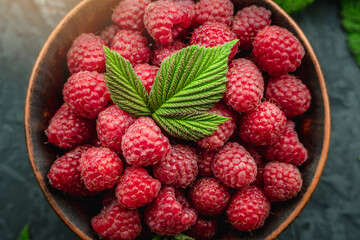 Fresh ripe juicy and appetizing raspberries in a bowl on a black background. Top view