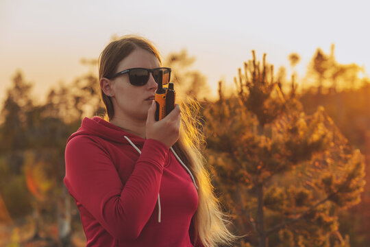 Woman using walkie talkie outdoors and relax on nature on forest background. Using portable handheld radio transceiver outdoor. Woman with CB radio.