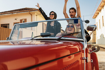 Friends traveling together in an old convertible car. Summer enjoyment concept