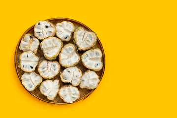 Custard apple in bamboo basket on yellow background.