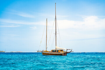 Stunning view of a wooden sailboat sailing on a beautiful turquoise sea during a sunny day. Isola...