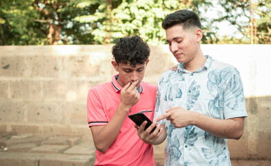 A young man explaining with his cell phone to a young man, A young man showing his cell phone to...