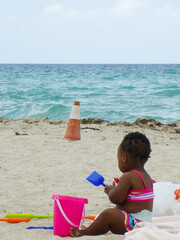 アメリカ・マイアミのビーチにて小さな子供が座って砂遊びする様子
