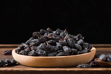 Dried fruits, pile of black raisins on table.