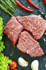 Raw fresh marbled beef meat, seasonings  on dark stone cutting board