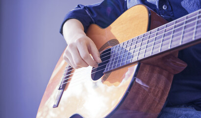 Close-up shot of a guitarist's hand on a blue background