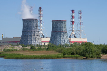 Cooling towers on the background of the building of the city Southwest CHP on a sunny June day,...