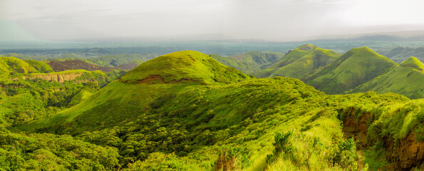 Image of a hill surrounded by other green hills, A path to a green hill with blue sky with copy space