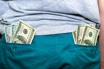two bundles of hundred-dollar bills in the pockets of denim trousers