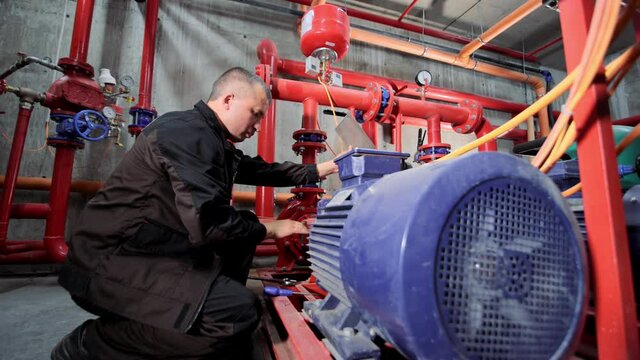 A water pumping station engineer repairs the water supply compressor engine.