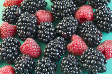 berries of blackberry and raspberry lie on a green background. a source of vitamins and minerals. wild and home berry