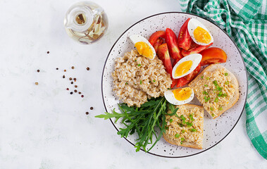 Fresh salad. Breakfast bowl with oatmeal, sandwiches with chicken rillettes, tomato and boiled egg. Healthy food. Top view, flat lay