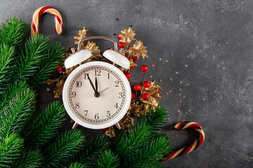 Christmas background with the inscription Christmas is coming. Clock, fir branches and christmas decorations on gray background, free space for text