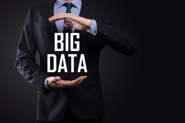 Businessman in a suit on a dark background holds the inscription BIG DATA. Storage Network Online Server Concept.Social network or business analytics representation