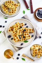 Croffle or croissant waffle, popular food made from croissant baked with waffle maker. Topping with blueberry and honey. Breakfast concept in bright mood photography.