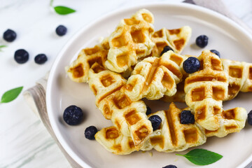 Croffle or croissant waffle, popular food made from croissant baked with waffle maker. Topping with blueberry and honey. Breakfast concept in bright mood photography.