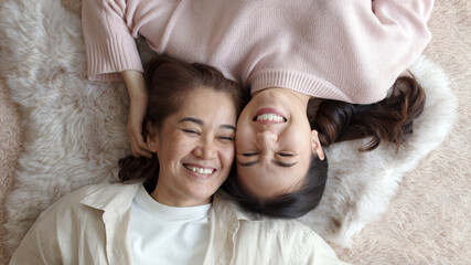 Attractive beautiful cheerful authentic real family two people laying down look at camera above tender emotion hug kiss cuddle relax comfort sleep in living room in health care healthy mother day.