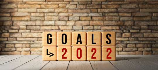 cubes with message GOALS 2022 on wooden base and brick wall background