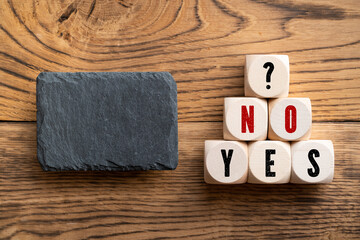 cubes with message YES - NO? on wooden background