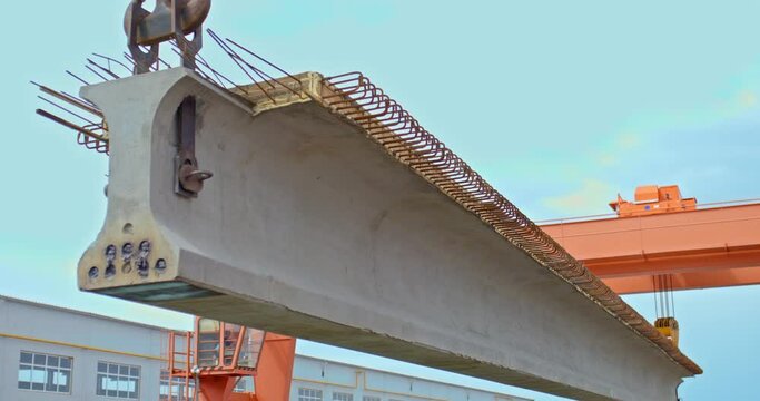 Close-up, a long concrete construction beam is lifted on a lift. Production and manufacture of concrete beams and structures for the construction of road bridges. 4k, ProRes