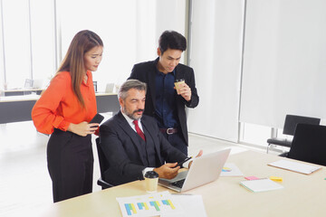 Fototapeta premium Senior male manager meeting and working with his colleagues in the team in front of his laptop at the office business discussion and project planning concept