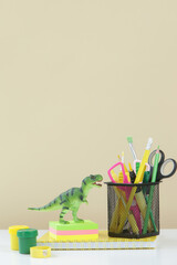 Education and back to school concept: notebooks with 
school stationery and green dinosaur toy on the table.
