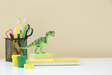Education and back to school concept: notebooks with 
school stationery and green dinosaur toy on...
