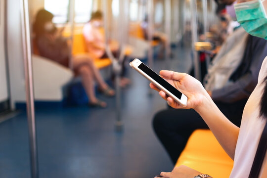 Young woman hand holding and using mobile phone inside subway train. Clipping path Display include in this image.