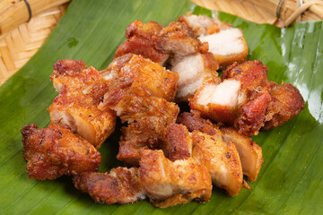 Deep fried pork belly with fish sauce placed on a banana leaf.