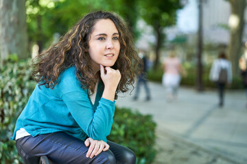 young woman thinking sitting on a bench in a turquoise blue sweater