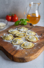 Ravioli with ricotta, spinach and basil prepared for cooking on a wooden board.