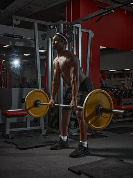 African american guy raises barbell with weights in gym. Strength training, losing weight, healthy lifestyle concept