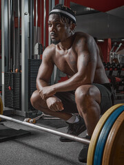 Obraz na płótnie Canvas Athletic sportive african american guy sitting squat with barbell in gym. Strength training, weightlifting