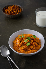Thick pumpkin soup with baked chickpeas and radish sprouts in a plate with a glass of milk on the table, delicious healthy dinner