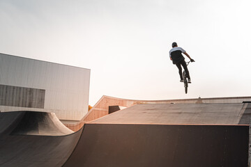 A young rider on a BMX bike does tricks in the air