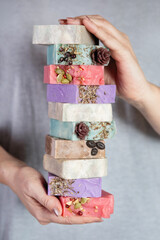 Female hands hold stack of handmade soap.