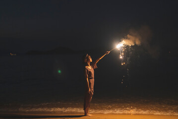 Fototapeta na wymiar 夕暮れの海で花火をする女性