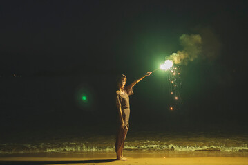 Fototapeta na wymiar 夕暮れの海で花火をする女性