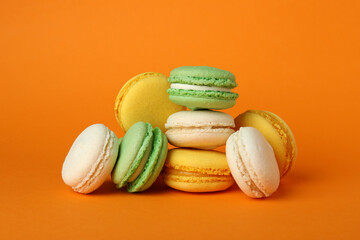 Concept of tasty dessert with macarons on orange background