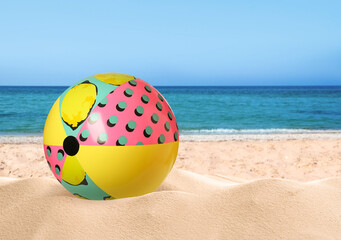 Fototapeta na wymiar Colorful beach ball on sandy coast near sea, space for text