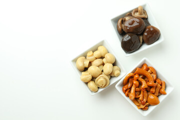 Bowls of marinated mushrooms on white background