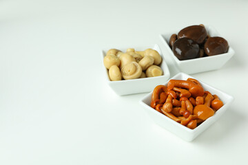 Bowls of marinated mushrooms on white background
