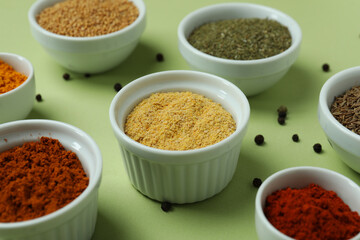 Set of different spices in bowls on green background