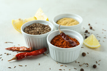 Aromatic spices in white bowls on textured background